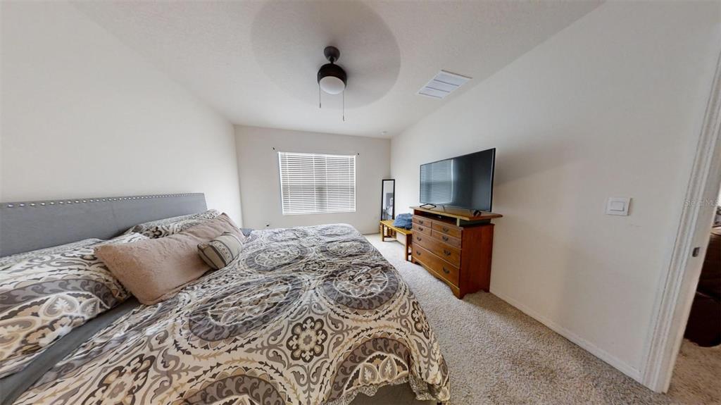 1818 Myrtlebrooke Drive Edgewater, FL 32141 - Photo 21 of 23 a bedroom with a large bed and a flat tv screen on a dresser