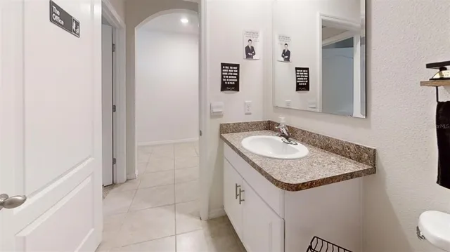 workspace with granite countertop a sink and a mirror