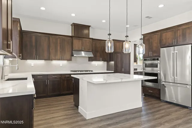 a kitchen with stainless steel appliances a stove a sink a refrigerator white cabinets and wooden floor