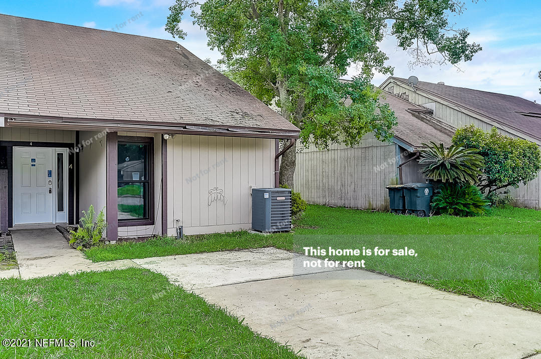 a view of a house with a yard plants and large tree