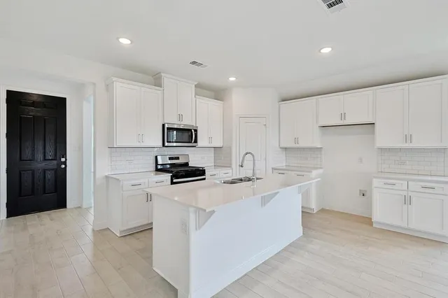 a kitchen with stainless steel appliances a stove a sink a refrigerator a microwave and cabinets