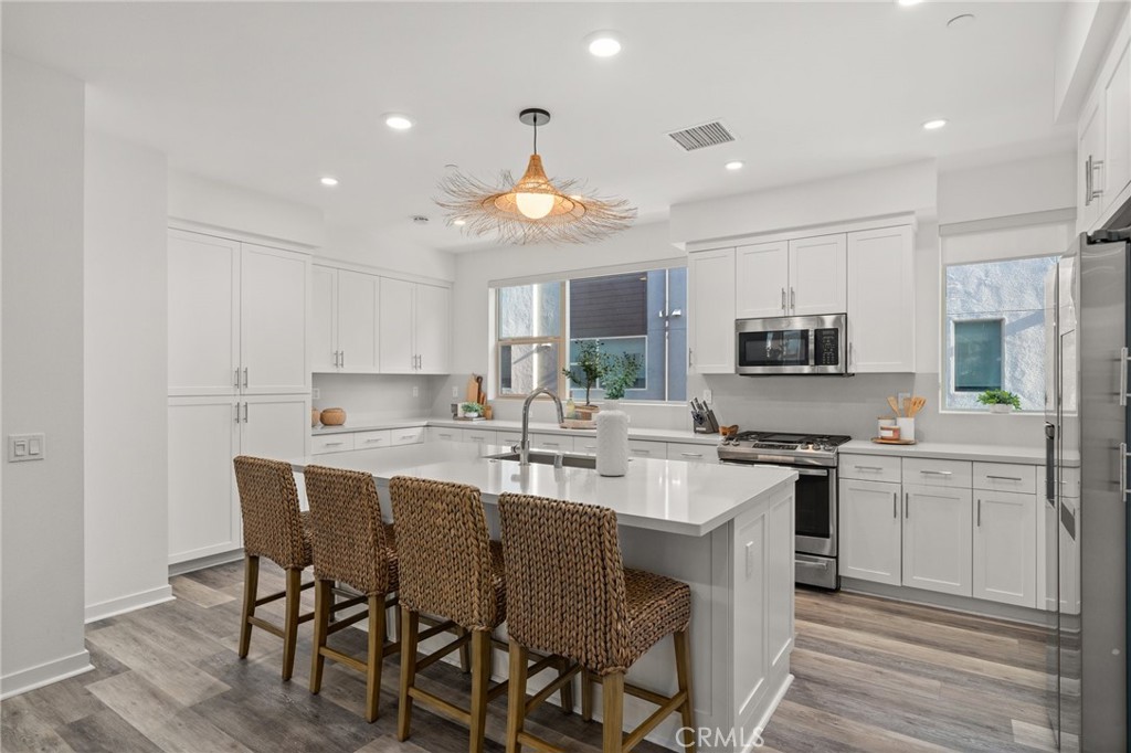 217 Placemark Irvine, CA 92614 - Photo 12 of 39 a kitchen with stainless steel appliances granite countertop a stove top oven a sink dishwasher and a refrigerator with wooden floor