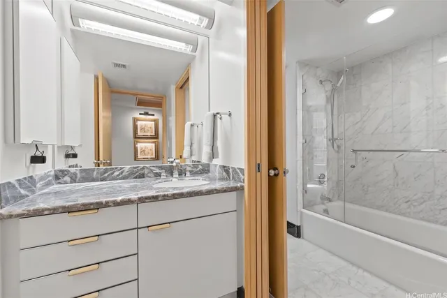 a bathroom with a granite countertop sink mirror and a bathtub