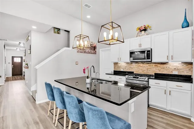 a kitchen with granite countertop a sink a stove and cabinets