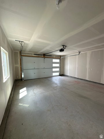 1225 West 500 South Logan, UT 84321 - Photo 18 of 39 Spacious garage with a modern white overhead door featuring frosted glass panels, durable concrete flooring, and a window providing natural illumination