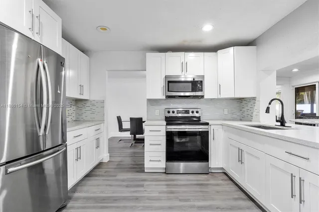 a large kitchen with stainless steel appliances granite countertop a stove a sink and a refrigerator