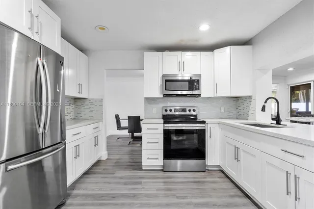 a large kitchen with stainless steel appliances granite countertop a stove a sink and a refrigerator