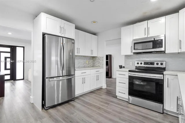a kitchen with granite countertop a refrigerator stove and wooden floor