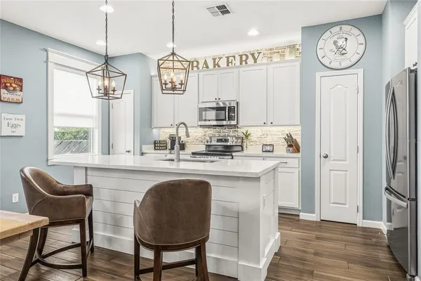 a kitchen with stainless steel appliances granite countertop a kitchen island a stove a dining table and chairs