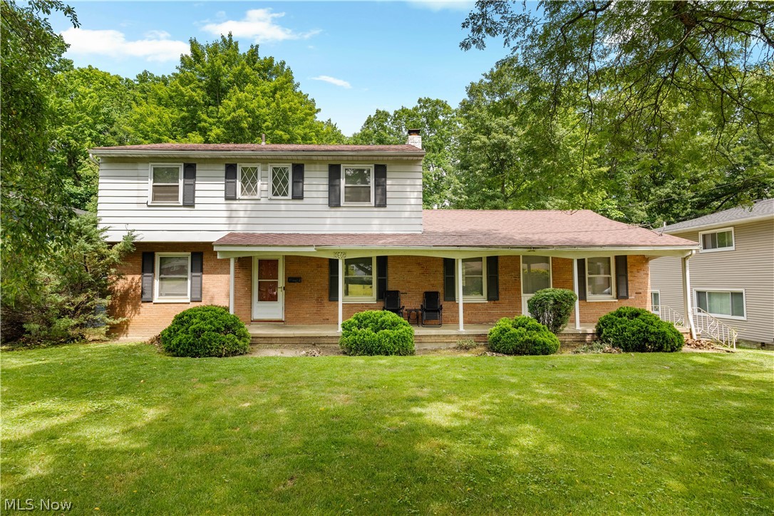 542 Garnette Road Akron, OH 44313 - Photo 1 of 24 Two-story residence featuring a brick and siding facade, a covered front porch, a well-maintained lawn, mature trees, and decorative window shutters