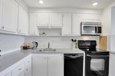 a kitchen with appliances a sink and cabinets