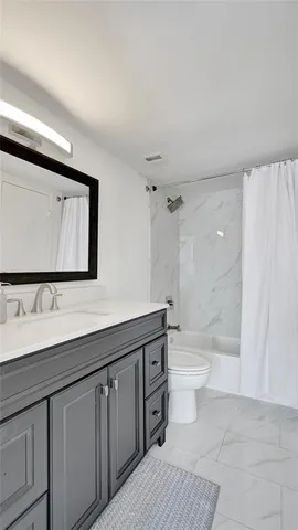 a bathroom with a toilet a sink a mirror a shower a vanity and window