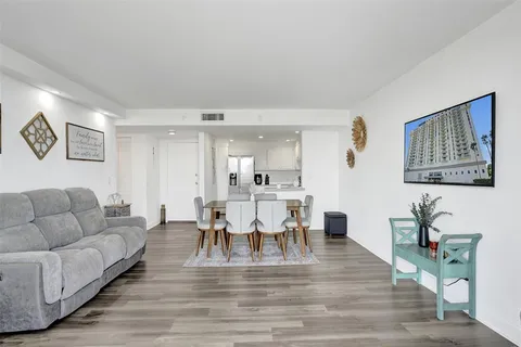 a living room with furniture and a dining table with wooden floor