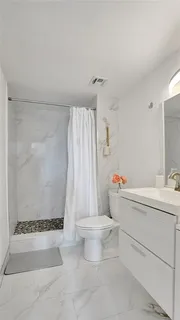 a bathroom with a sink a toilet and shower