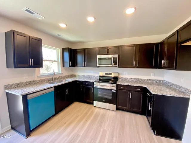 a kitchen with stainless steel appliances granite countertop a sink stove microwave and refrigerator