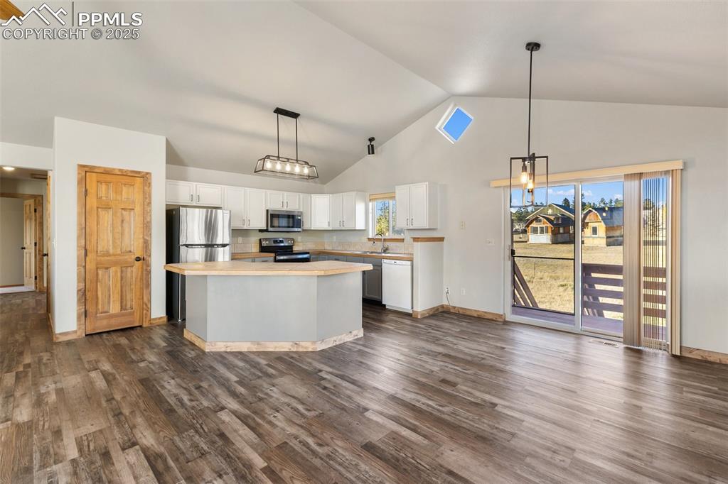 1380 Rampart Range Road Woodland Park, CO 80863 - Photo 6 of 30 a kitchen with stainless steel appliances kitchen island granite countertop a refrigerator a stove top oven and a wooden floors