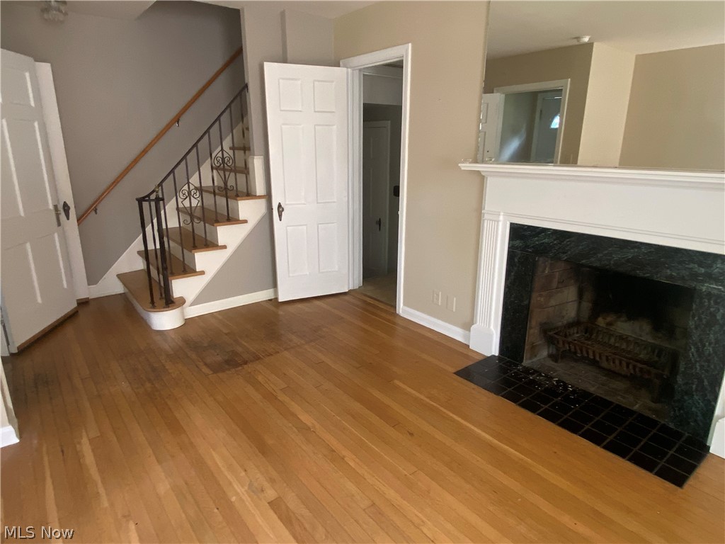 Hardwood flooring, fireplace with a decorative mantel, ornate wrought iron stair railing, and paneled interior doors