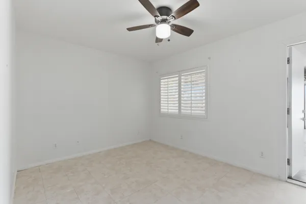 an empty room with a window and a fan