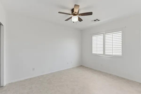 an empty room with a window and a fan