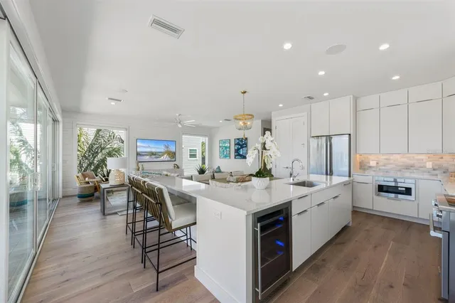 a view of a kitchen with kitchen island a large counter top space a sink stainless steel appliances and windows