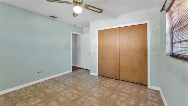 an empty room with windows and fan