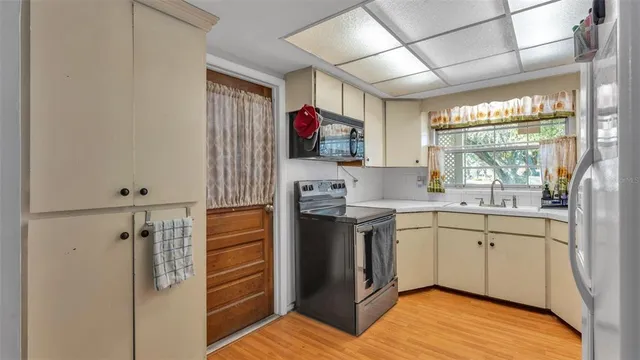 a kitchen with a sink appliances cabinets and a large window