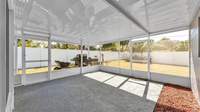 a view of an empty room with a floor to ceiling window next to a yard