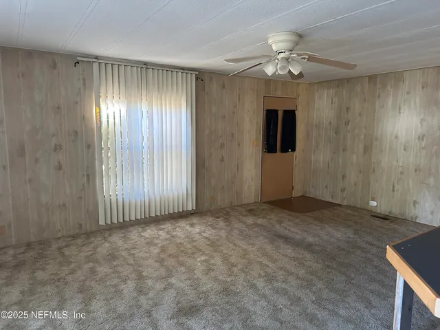 an empty room with chandelier fan and windows