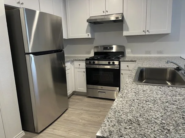 a kitchen with a refrigerator sink and cabinets
