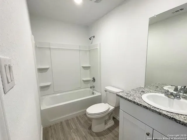 a bathroom with a granite countertop toilet a sink and a bathtub