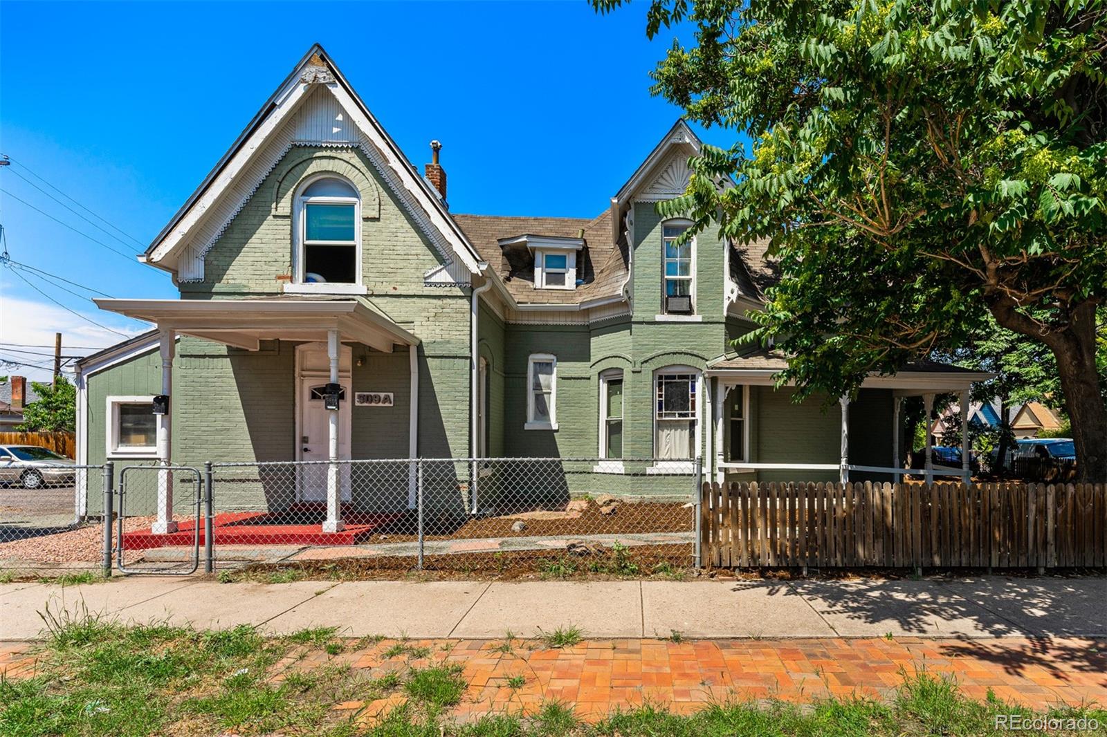 603 Elati Street Denver, CO 80204 - Photo 5 of 12 a view of a white house with large windows and plants next to a yard