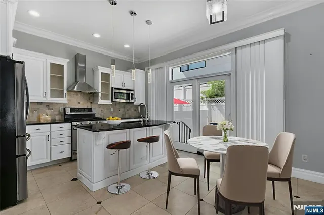 a kitchen with stainless steel appliances granite countertop a stove top oven a sink dishwasher a dining table and chairs with wooden floor