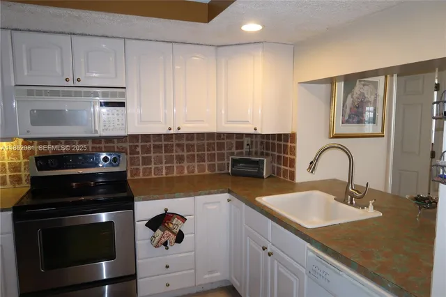 a kitchen with granite countertop white cabinets and black appliances