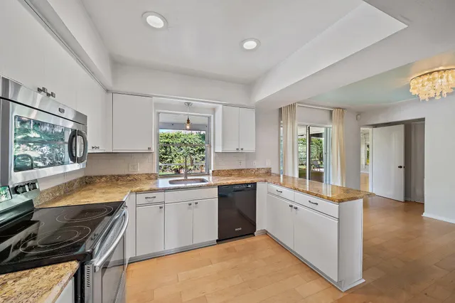 a large kitchen with granite countertop a stove top oven a sink a dining table and chairs