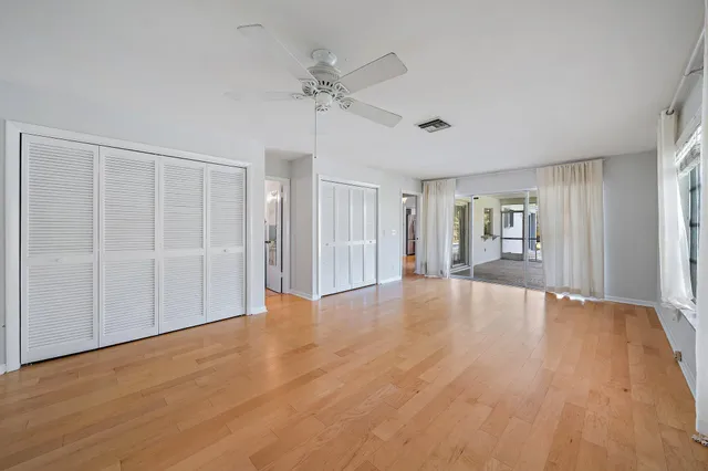 a view of an empty room with wooden floor and a bathroom