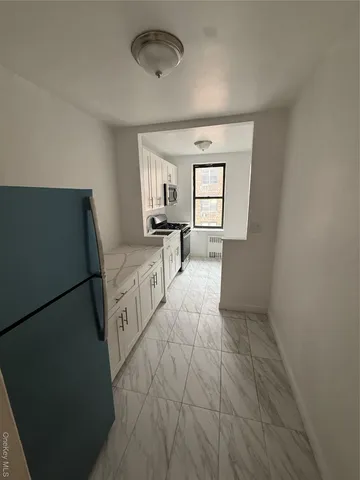 a room with a bed and a view of kitchen