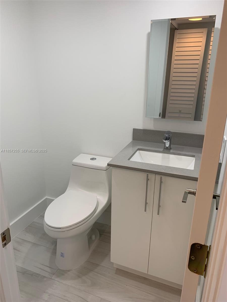6825 Southwest 45th Lane, Unit 7 Miami, FL 33155 - Photo 13 of 30 a bathroom with a toilet sink and mirror