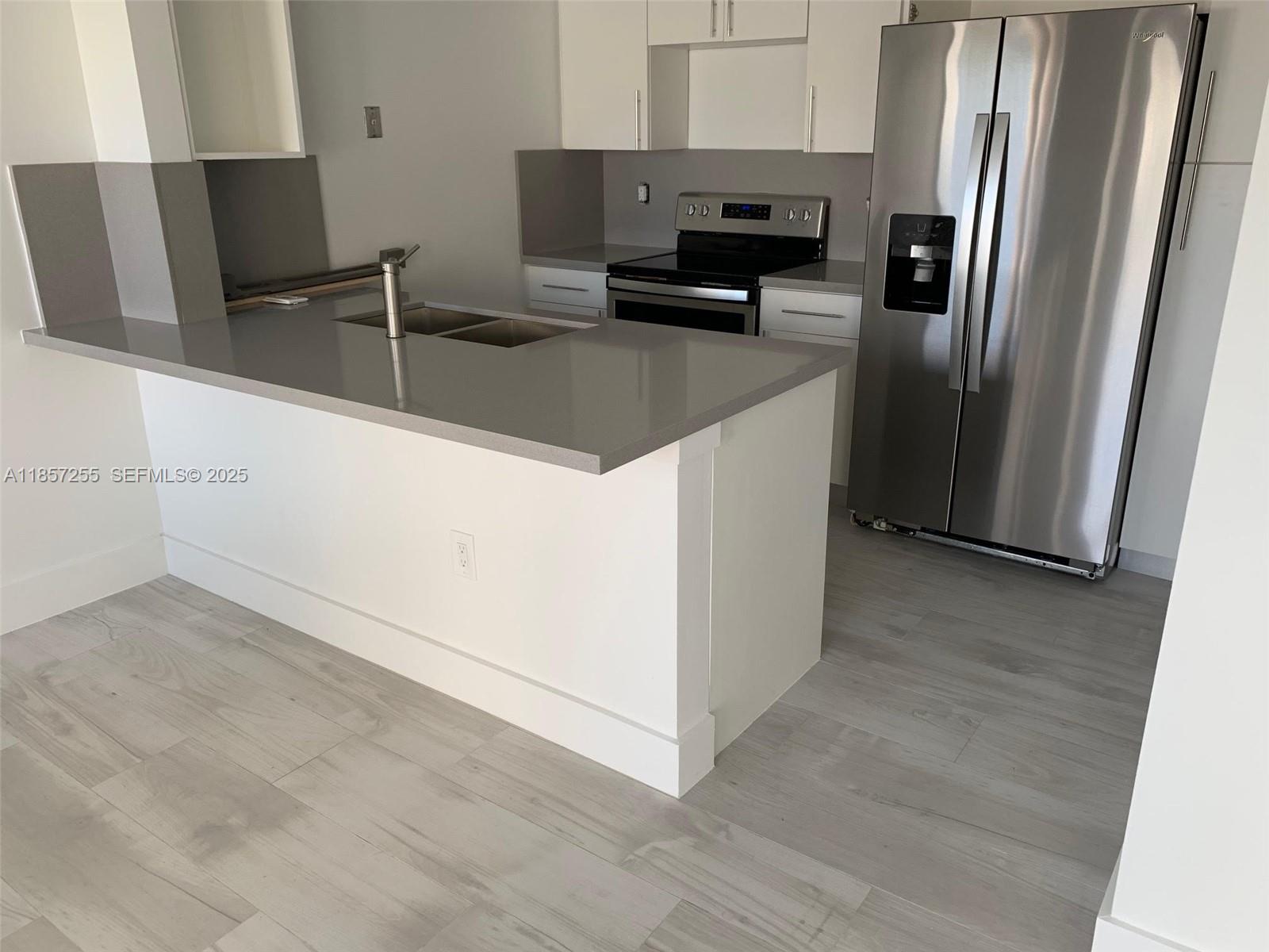 6825 Southwest 45th Lane, Unit 7 Miami, FL 33155 - Photo 4 of 30 a kitchen with stainless steel appliances a refrigerator a sink a stove and white cabinets