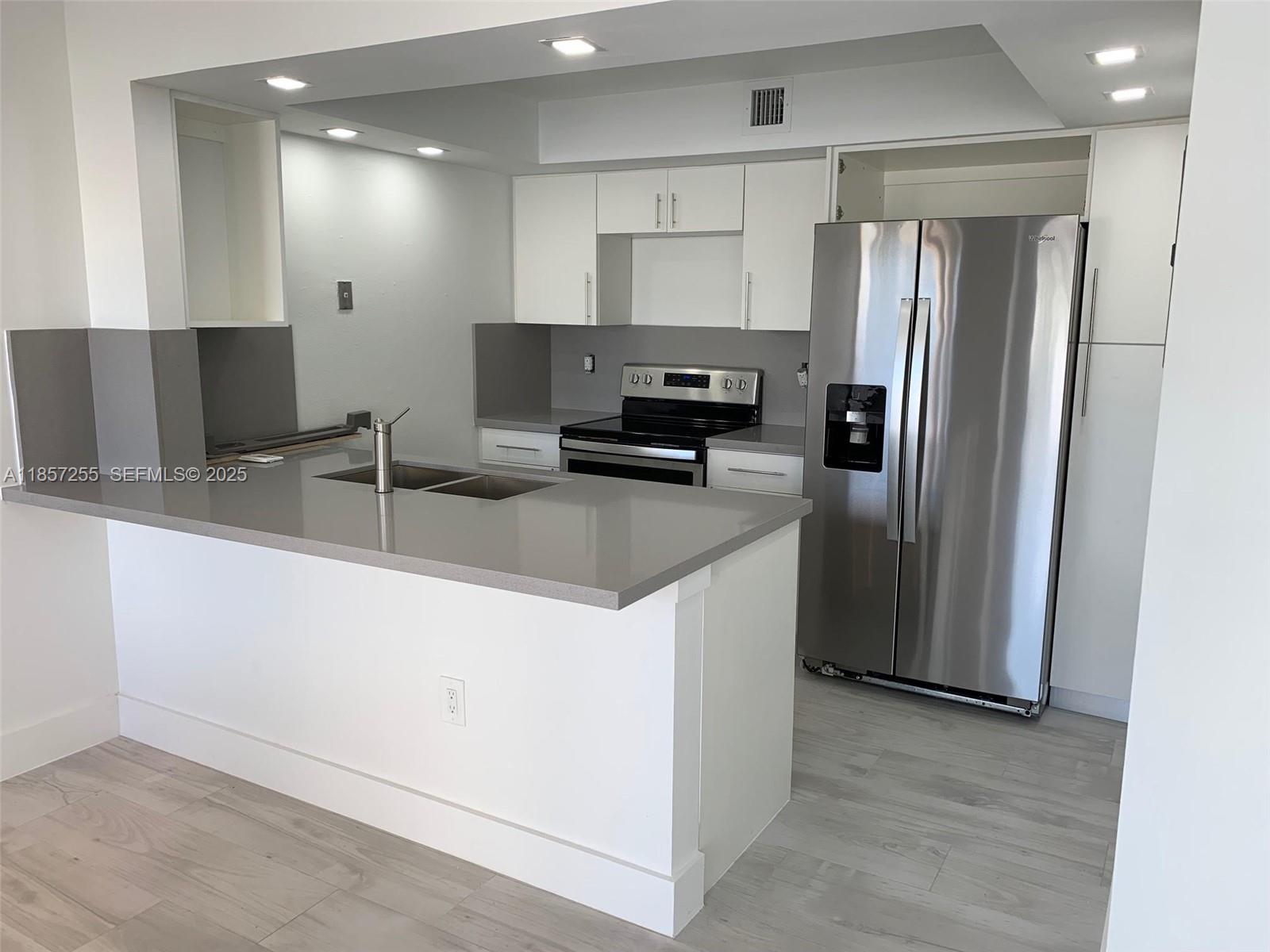 6825 Southwest 45th Lane, Unit 7 Miami, FL 33155 - Photo 5 of 30 a kitchen with stainless steel appliances granite countertop a refrigerator a sink a stove a microwave and island