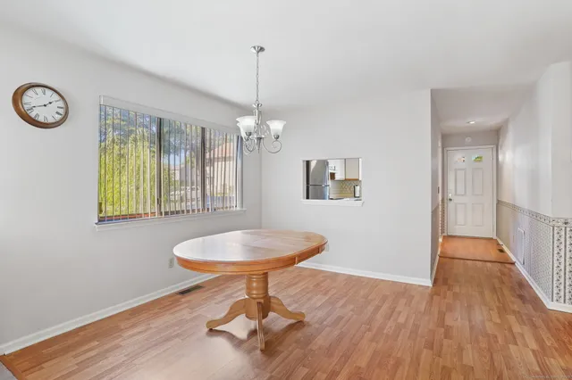 a view of a room with a wooden floor a chandelier a kitchen space and a chandelier