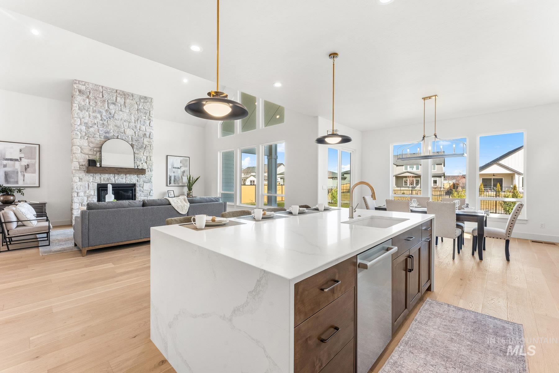 6954 Saddle Bred Way Star, ID 83669 - Photo 13 of 49 Kitchen featuring light wood finished floors, a fireplace, light stone countertops, a kitchen island with sink, and stainless steel dishwasher