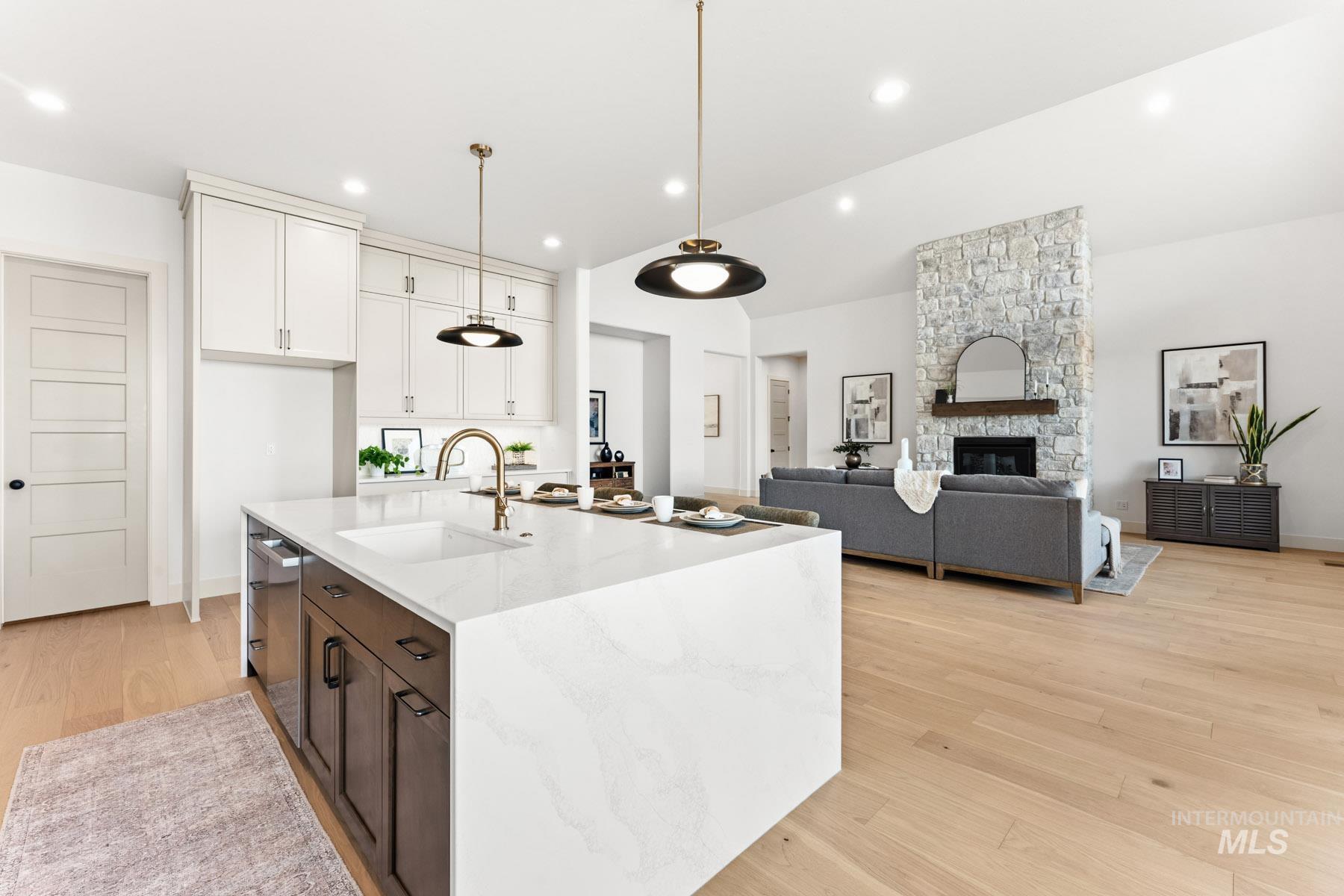 6954 Saddle Bred Way Star, ID 83669 - Photo 49 of 50 Kitchen with light wood-style floors, light stone countertops, a stone fireplace, an island with sink, and open floor plan