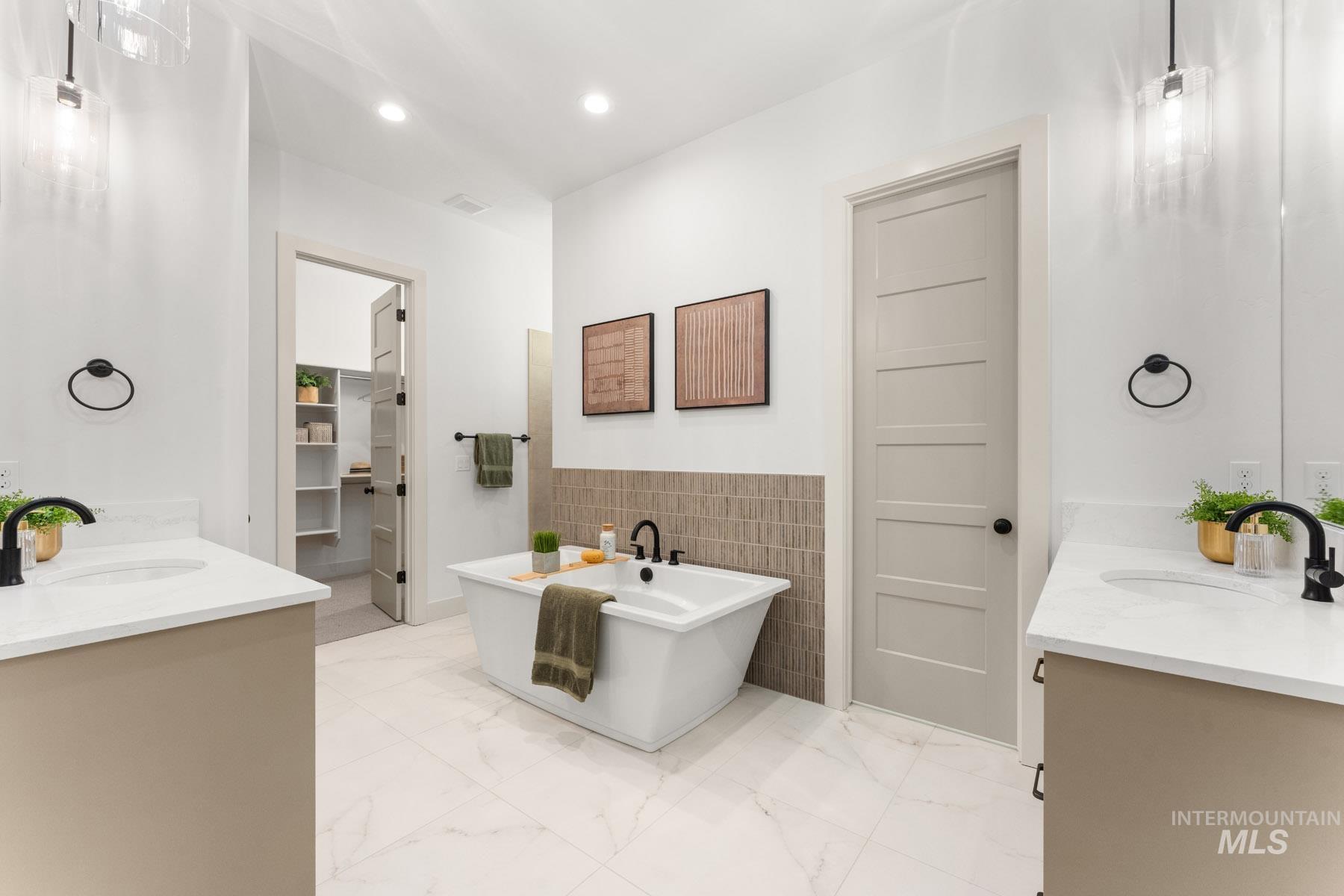 6954 Saddle Bred Way Star, ID 83669 - Photo 22 of 50 Bathroom with two vanities, a soaking tub, tile walls, light marble finish flooring, and a spacious closet