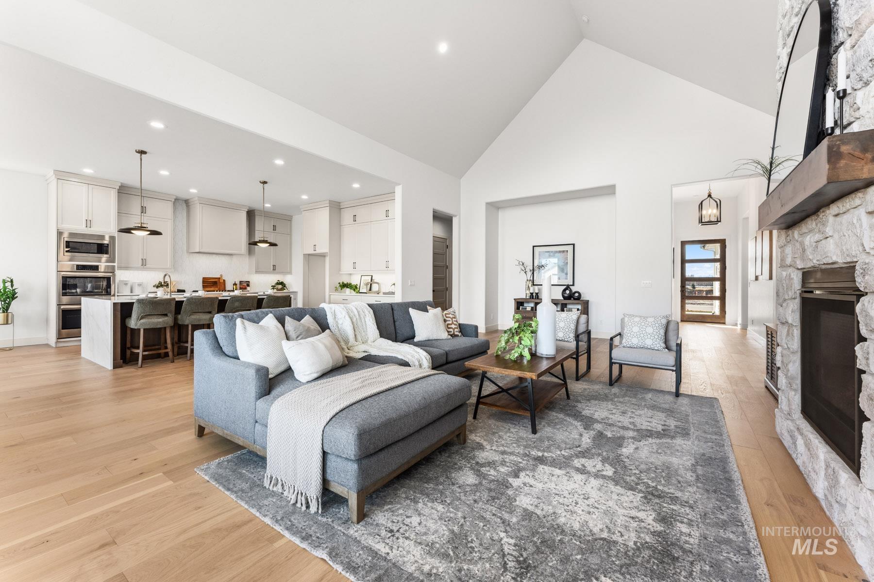 6954 Saddle Bred Way Star, ID 83669 - Photo 9 of 50 Living room with a stone fireplace, light wood-style flooring, a high ceiling, and recessed lighting