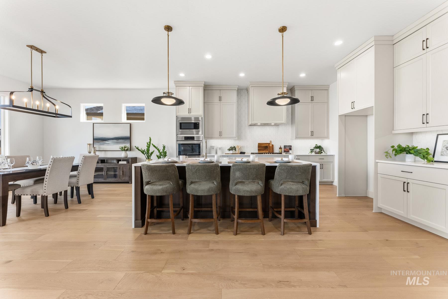 6954 Saddle Bred Way Star, ID 83669 - Photo 10 of 50 Kitchen featuring a kitchen breakfast bar, light wood-style floors, pendant lighting, a kitchen island with sink, and stainless steel appliances