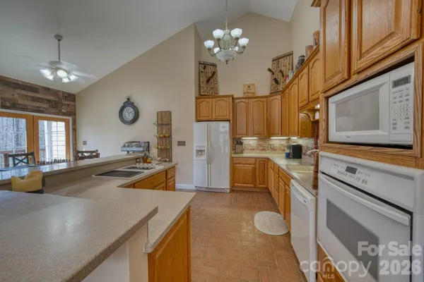 a view of a kitchen with kitchen island a refrigerator a stove a sink and dishwasher with wooden floor