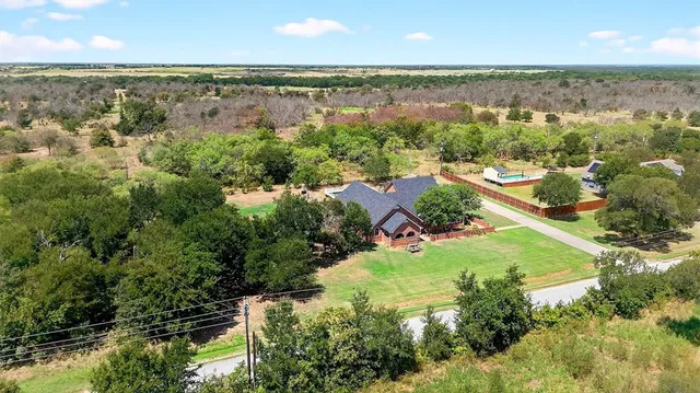 an aerial view of ocean and residential houses with outdoor space and trees