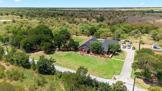 an aerial view of residential houses with outdoor space and trees