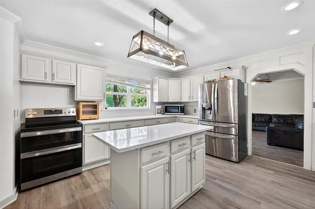 a kitchen with kitchen island a counter space a stove and a refrigerator