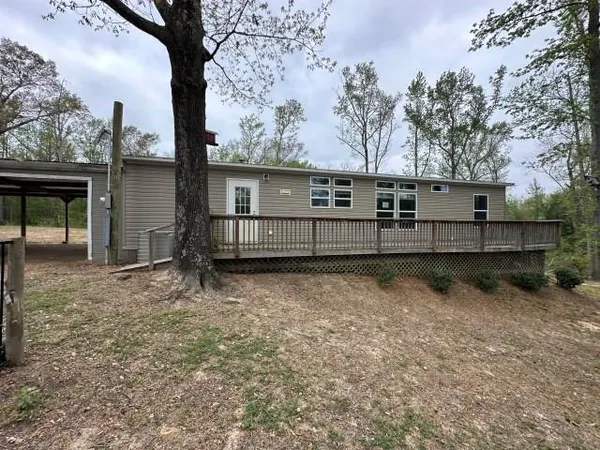 a view of house with large trees and wooden fence
